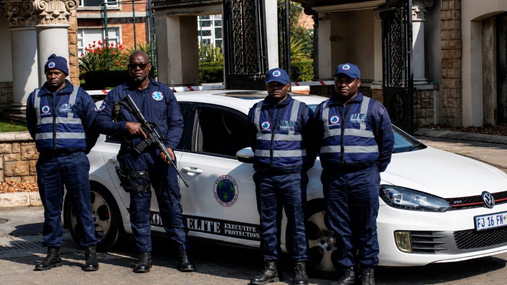 Armed Global Elite security officer standing near branded patrol vehicle