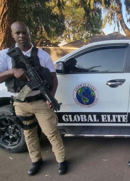Armed Global Elite security officer standing near branded patrol vehicle